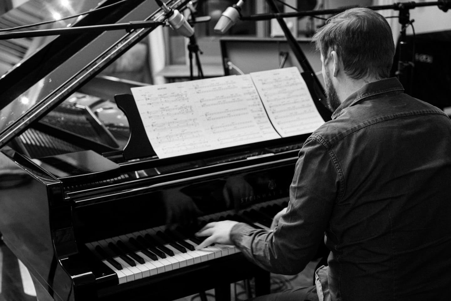 A pianist plays a grand piano during a recording session.